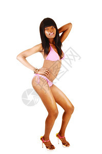 一个可爱的非裔美国女人穿着粉红色比基尼和高跟鞋在工作室里为白人背景图片