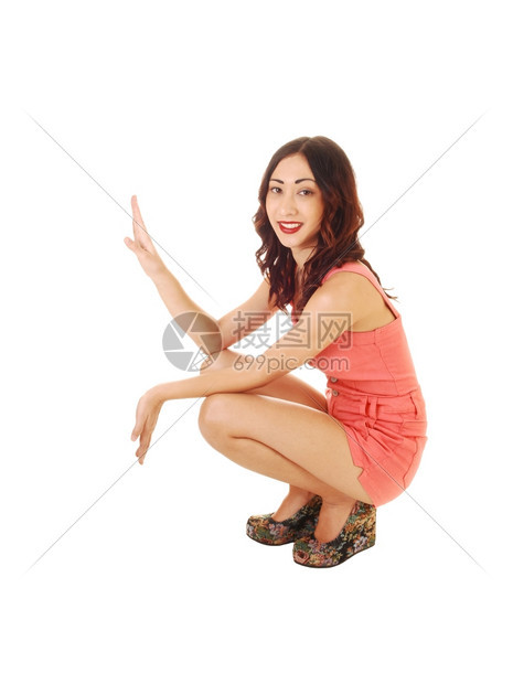 一个穿着短裤的可爱年轻女人跪在地上穿着高跟鞋长的黑发白背景图片