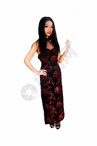 一位美丽的年轻女人穿着长的黑红裙子的黑头发站在白色背景图片