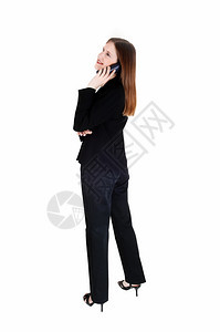 一个高瘦的年轻女商人站在黑色西装侧写电话上讲白背景图片