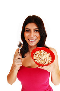 一个漂亮的黑发年轻女人穿着红色T恤手里拿着一碗麦片做早餐图片