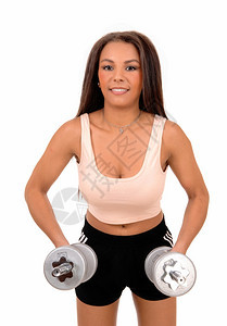 一位穿黑短裤的漂亮女人站在白背景面前举起两个哑铃来锻炼图片