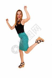 一个穿着绿衬衫的可爱年轻女人穿着黑色上衣在工作室里跳舞图片