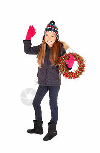 一个穿着夹克编织帽子和手套的可爱年轻女孩用她的手放下拿着一个冒险花圈与白种背景隔绝图片
