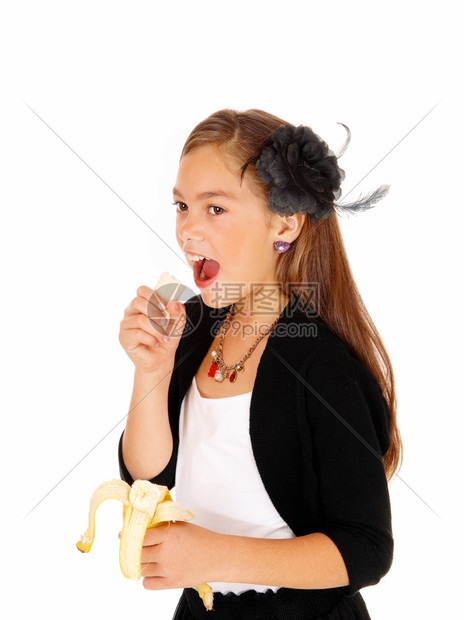 一个8岁女孩手里拿着香蕉吃东西被白种背景隔绝图片