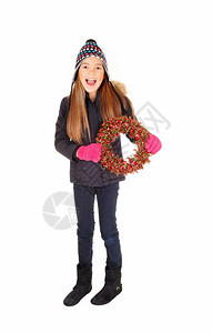 一个穿着夹克编织帽子和手套的可爱女孩拿着一个冒险花圈与白种背景隔绝图片