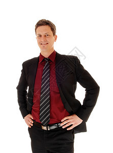 一个身穿西装的商人站在一个孤立的白人背景手放在他的臀部和微笑图片