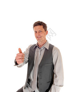 一个商人坐在灰色的衬衫和背心做OK标志和微笑孤立的白色背景图片