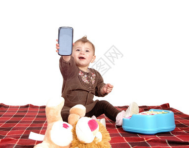 一个小女孩坐在地板上的毯子带着她的玩具妈的手机图片