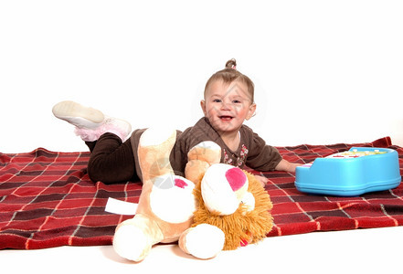 一个穿着棕色礼服的可爱女婴躺在地板上的毯子为了白色背景而孤立无援图片
