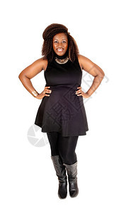 一个漂亮的非洲裔美国女人站在黑色的裙子紧身裤和靴微笑孤立的白色背景图片