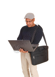 一名西班牙裔中年男子站在孤立的西班牙人白背景工作在他的笔记本电脑上用他的包在肩膀上图片