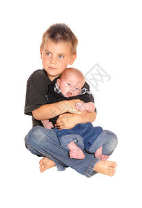 一个小男孩坐在地板上抱着他的新三个星期哥在他大腿上孤立白色背景图片