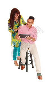 一位西班牙裔男子和高加索女看着平板电脑站在他身后被白种背景隔离图片