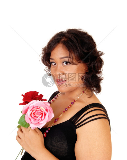 一位美丽的混合种族年轻女子拿着红玫瑰和粉在肖像拍摄中与白背景隔绝图片