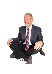 一个笑的中年商人穿着西装坐在地上被白种背景孤立图片