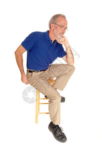 他五十几岁时身穿米色裤子坐在椅上穿着蓝色T恤手放在下巴上图片