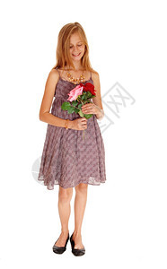 一个漂亮的年轻女孩穿着勃根底裙子拿着两朵玫瑰微笑着孤立的白种背景图片