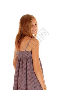 一个可爱的金发年轻女孩站在白背景的孤立穿一件勃根迪礼服仰望着她的肩膀图片