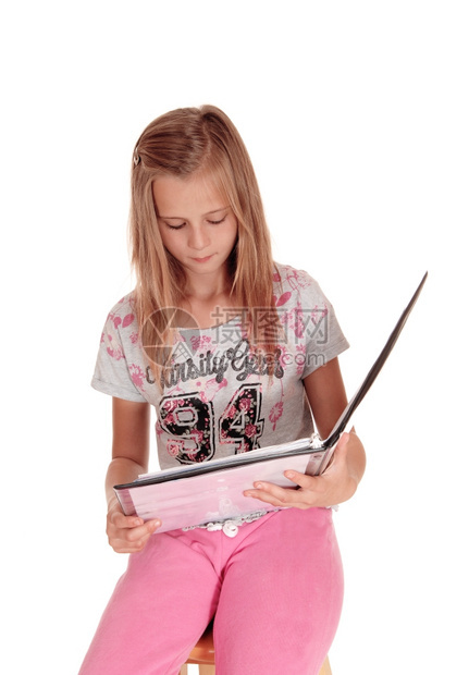 一个穿着粉红色裤子的金发年轻女孩拿着她的皮夹读书被白背景隔离图片