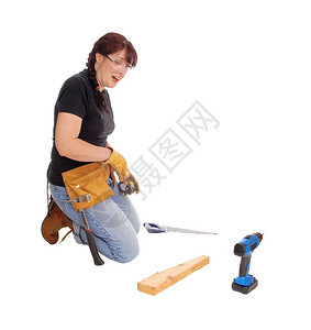 一位中年妇女跪在地上用一些工具作为白种背景而孤立无援图片