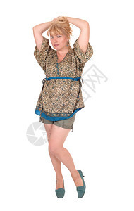 一名中年金发女子站在前面的短裤里手放在头上因白种背景而孤立无援图片