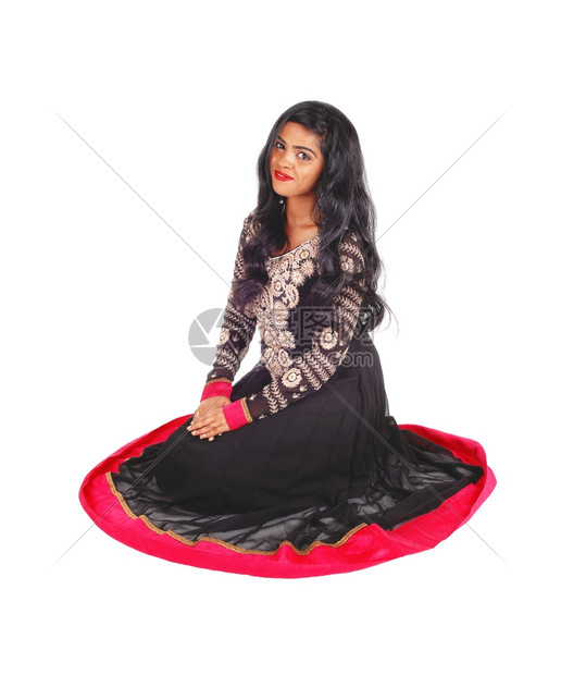 一个美丽的印度女人身着土生长的黑色裙子的黑色头发在地板上隔离为白色背景图片