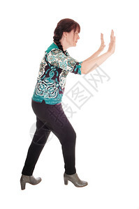 一个漂亮的中年女站立在形象上双手举起推着东西离开孤立的白色背景图片