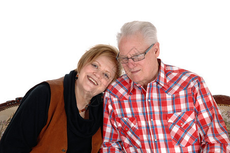 一位年长的老公民夫妇坐在沙发上妻子戴头巾站在丈夫的肩膀上因白种背景被隔离图片