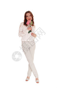 一位美丽的年轻高加索女穿着带子上衣和黑褐色头发手握着粉红玫瑰与白种背景隔绝图片