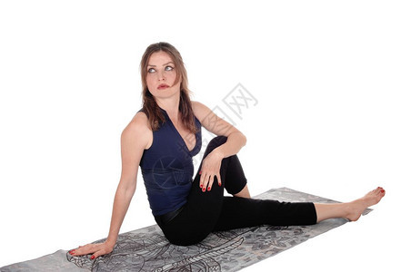 一个穿着运动服的年轻美女坐在地板上的毛巾在锻炼后休息与白种背景隔绝图片
