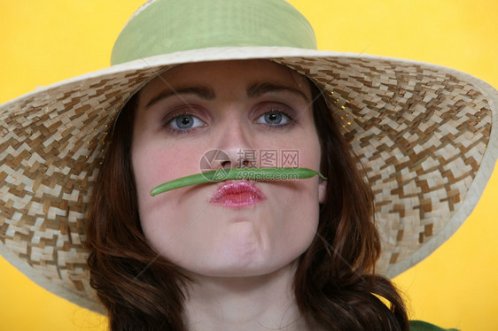 女人在嘴唇和鼻子之间平衡绿色豆子图片