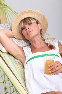 女人躺在吊床上喝水果鸡尾酒图片