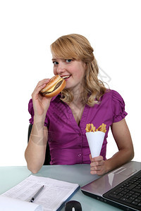女人在桌子边吃芝士汉堡和薯条图片