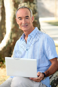 带笔记本电脑在公园的灰色头发男子图片