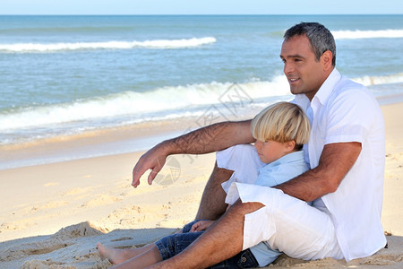 父亲和儿子坐在沙滩上图片