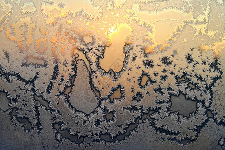 美丽的冰面图案和明光阳紧贴冬季玻璃窗图片