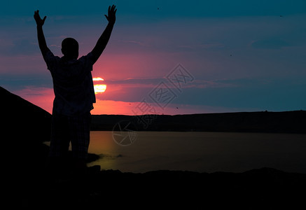 男人欢迎日落的太阳举起手来图片