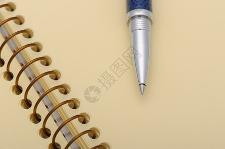 笔和记本在黄纸的螺旋上图片