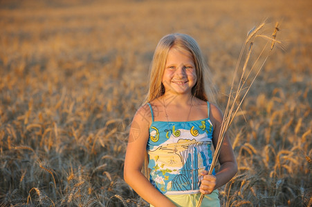 女孩在小麦中温暖的日落图片