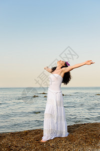 穿着白遮光衣的女人在海边滨上张开双手风景美图片