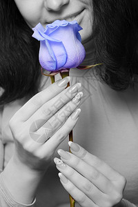 s图像拿着蓝玫瑰的女人特写女人和一朵彩色玫瑰的单色图像背景