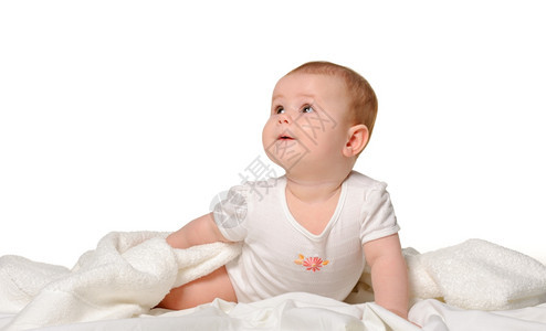 婴儿在床单上8个月大在白色背景上被隔离图片