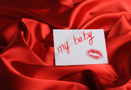 红色丝绸上的记号面写着我的宝贝和唇印用口红画图片