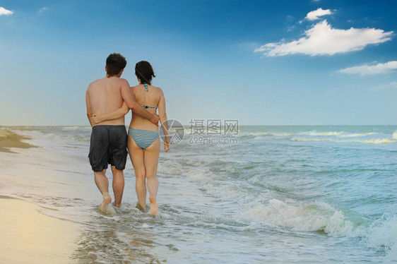 海岸对面的滨边黑的男孩和在海岸上行走的女孩图片