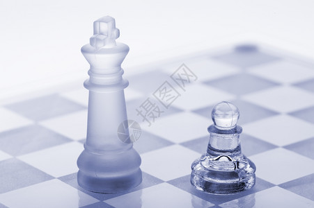 玻璃象棋子和国王蓝色的白隔离在背景上图片