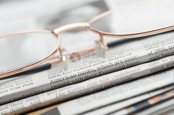 眼镜就躺在一堆报纸上照片近在眼前有选择的焦点图片