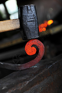 铁匠在铁炉里锻造一个烧红的铁图片