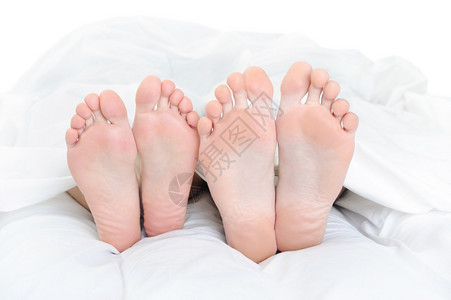 在床上的一对夫妇双脚紧关着孤立在白色背景上图片