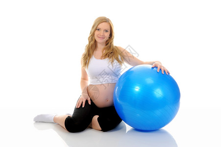美丽的年轻怀孕少女用蓝色球做运动练习图片